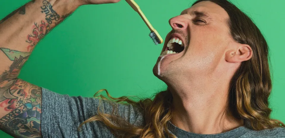 Canary lifestyle photography: brushing with a bamboo toothbrush against a green backdrop
