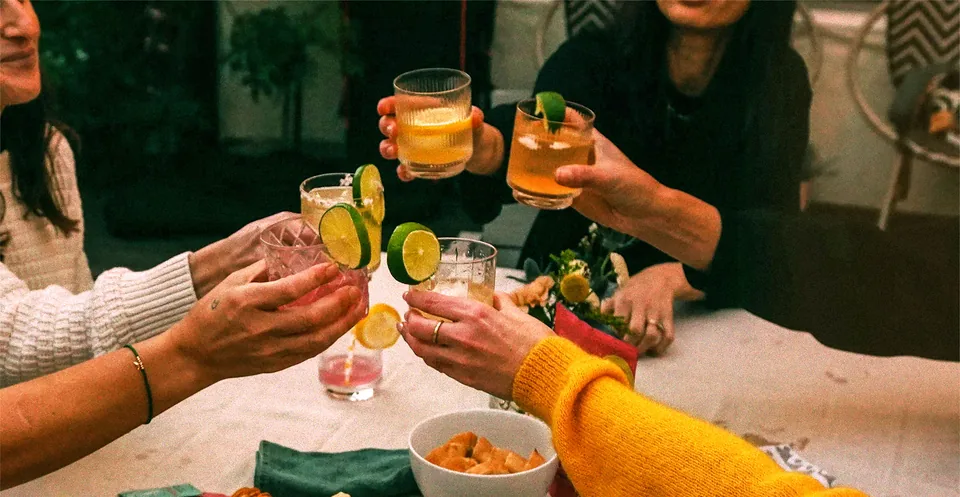 Creative direction reference: friends raising colorful drinks around a table