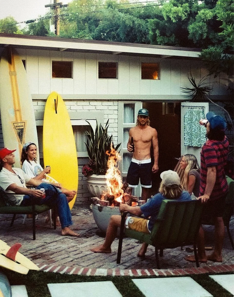 Creative direction reference: friends gathered around a fire outside a beach house